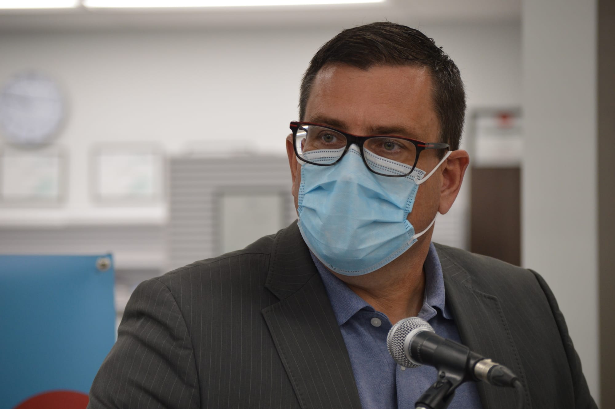 Former Saskatchewan Health Minister Paul Merriman stands in front of a microphone. 