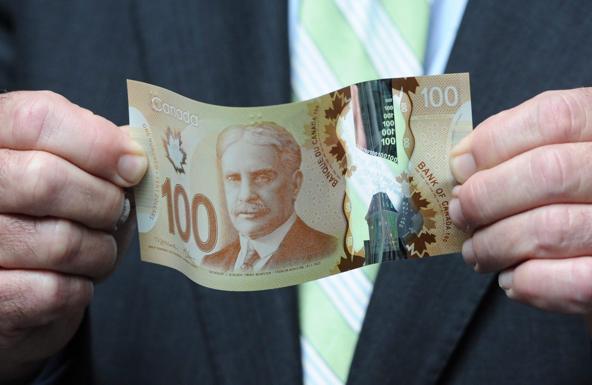 Man holds a $100 Canadian bill.