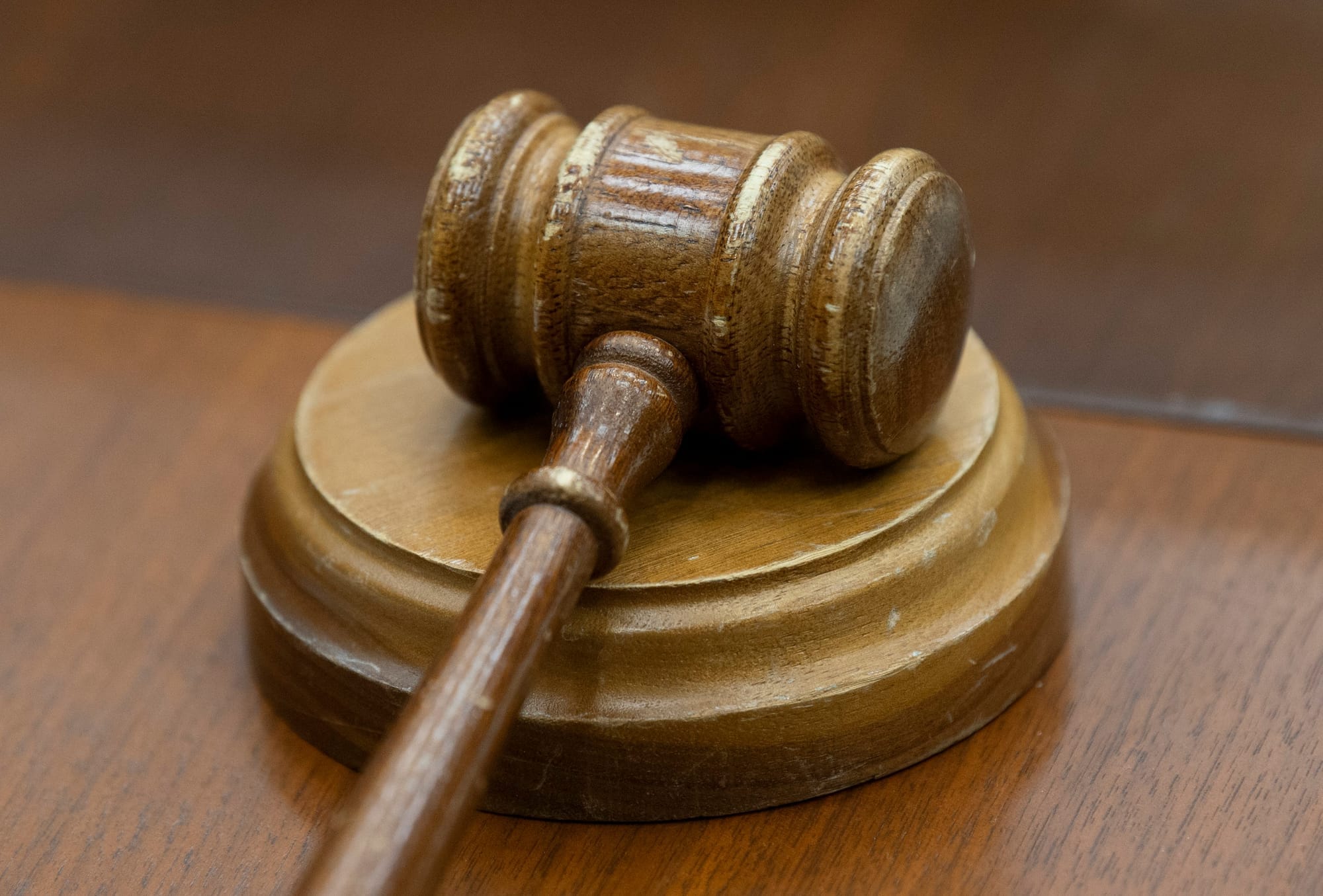 A judge's wooden gavel rests on a block atop a desk. 