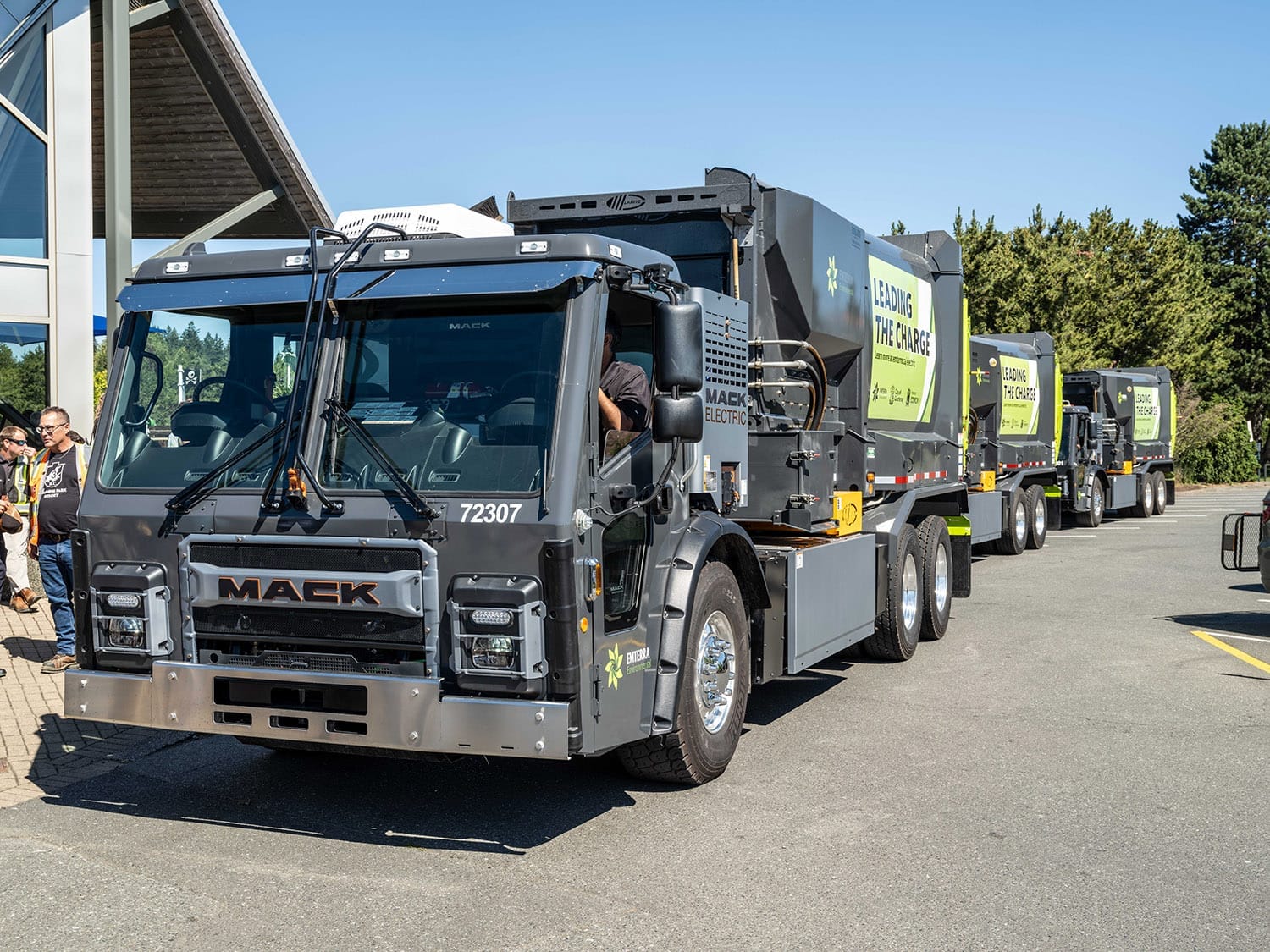 Three Emterra electric waste collection trucks are parked back to back