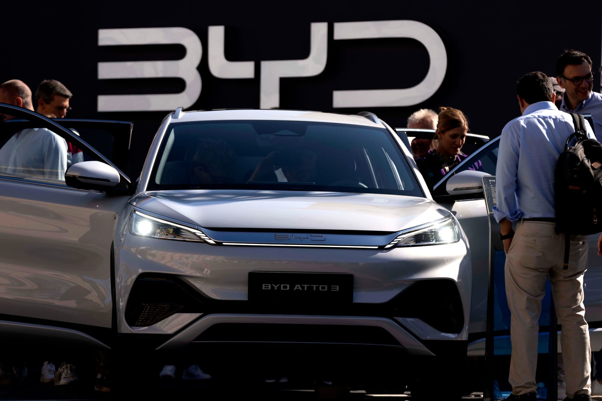 People look at a silver BYD vehicle with its doors open