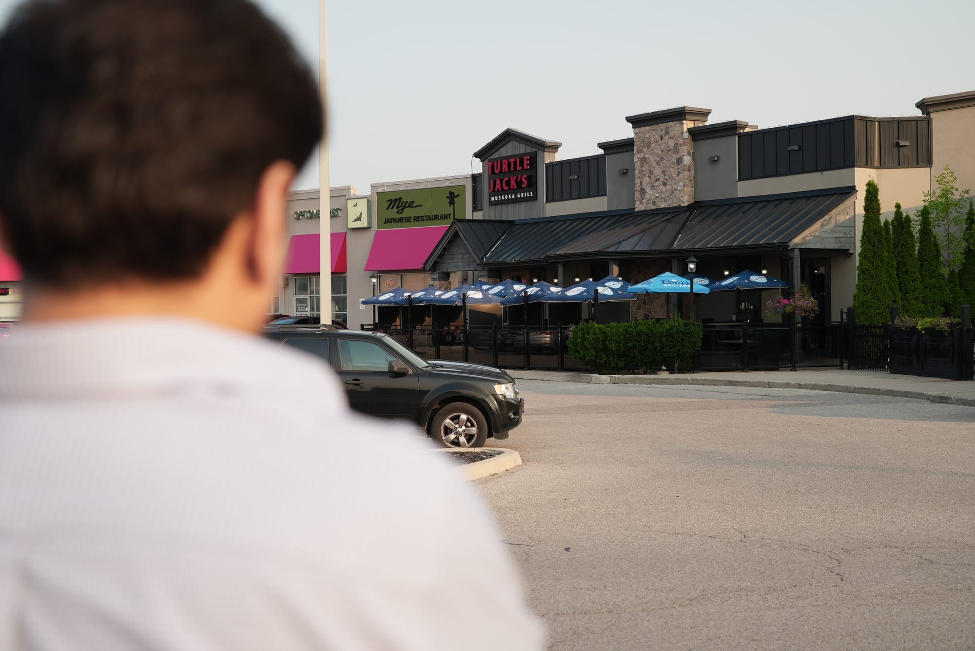 A person, out of focus, faces away from the camera while looking at the front entrance for Turtle Jack’s in Oakville, Ont.