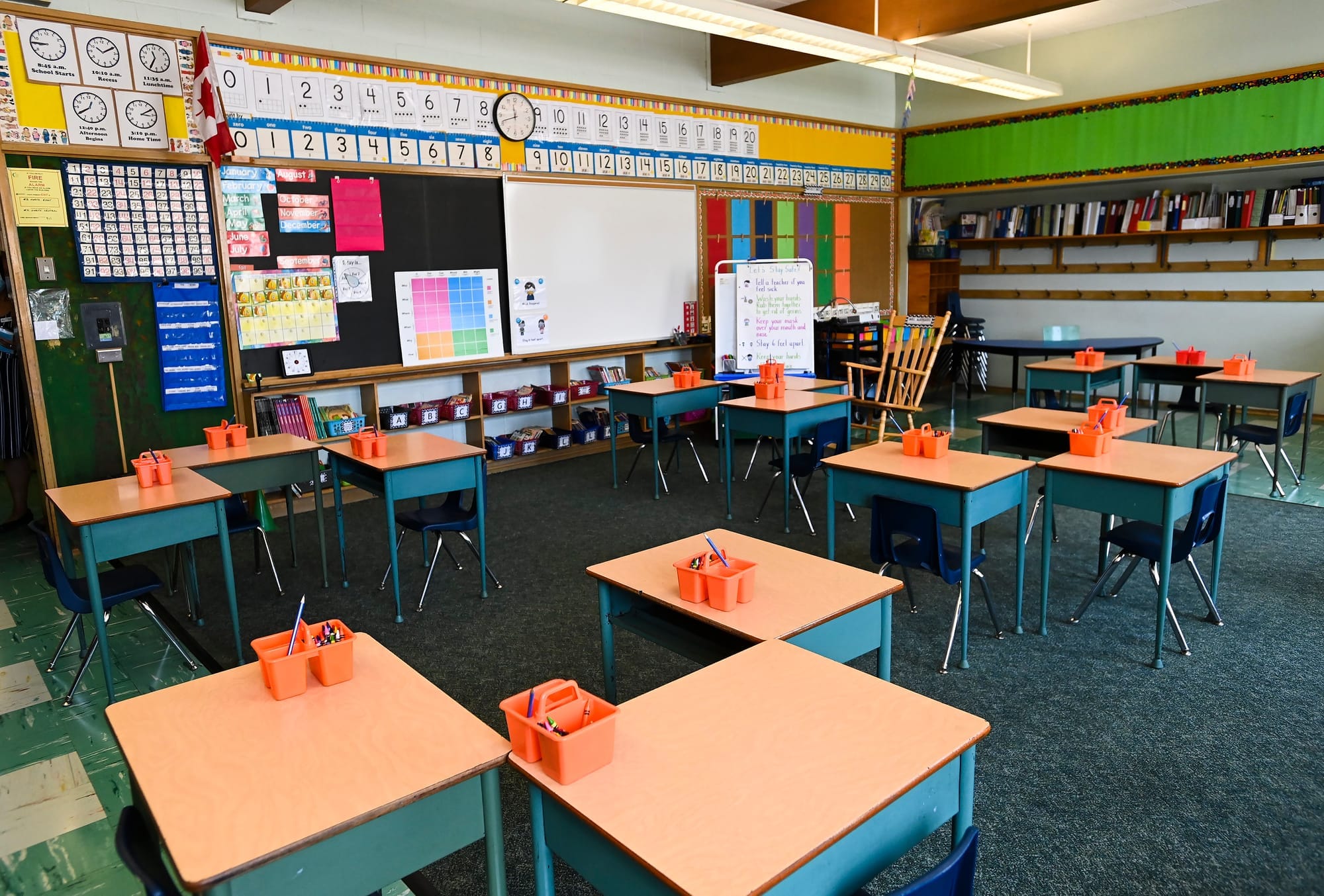 Desks are arranged in front of a white board in an empty classroom 