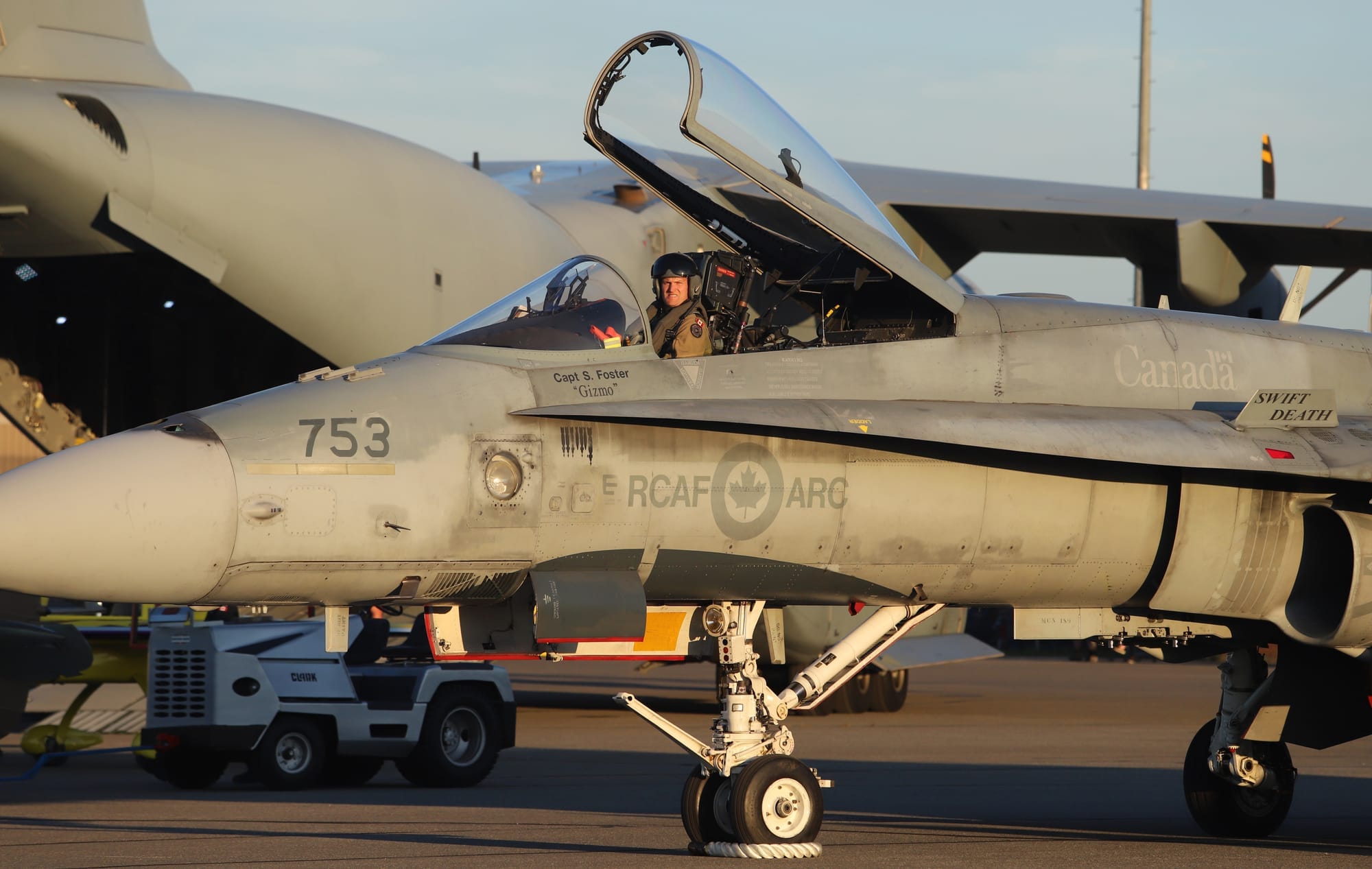 A pilot sits in a Royal Canadian Air Force plane stationary on the tarmac.