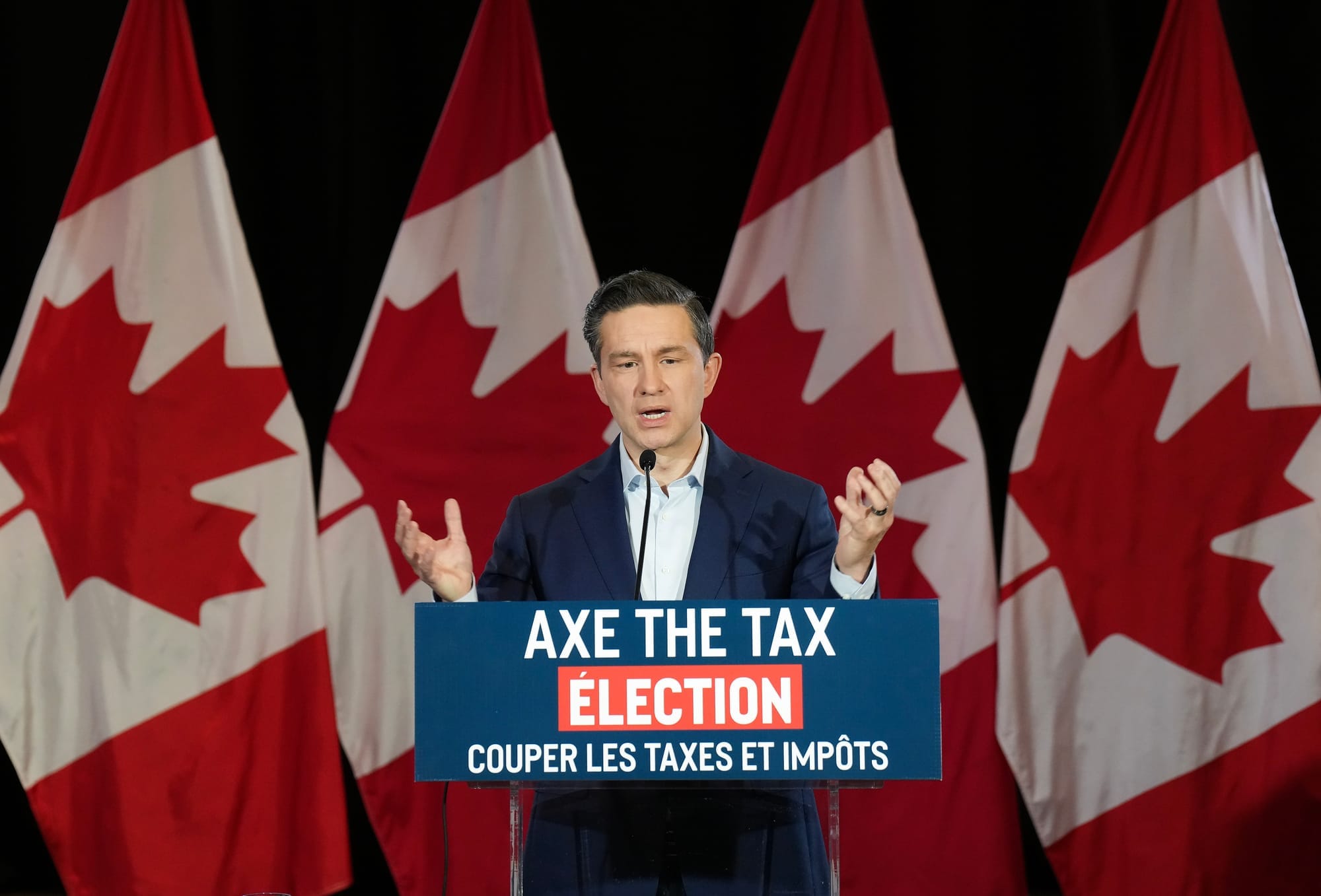 Conservative Leader Pierre Poilievre stands at a podium with an "Axe the Tax Election" sign.