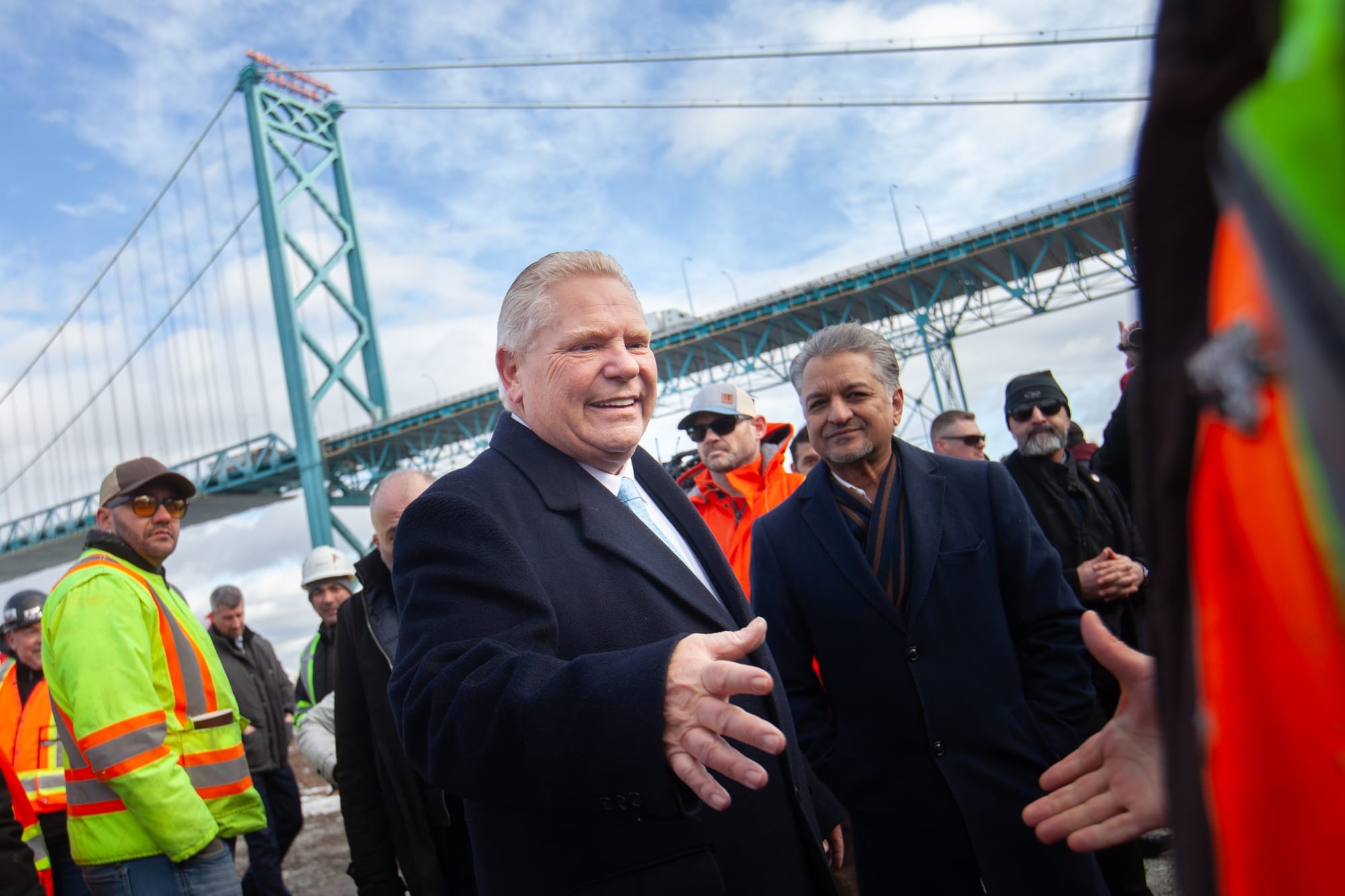 Doug Ford shakes hands with a supporter as he stands in a crowd of men wearing high-vis construction vests.