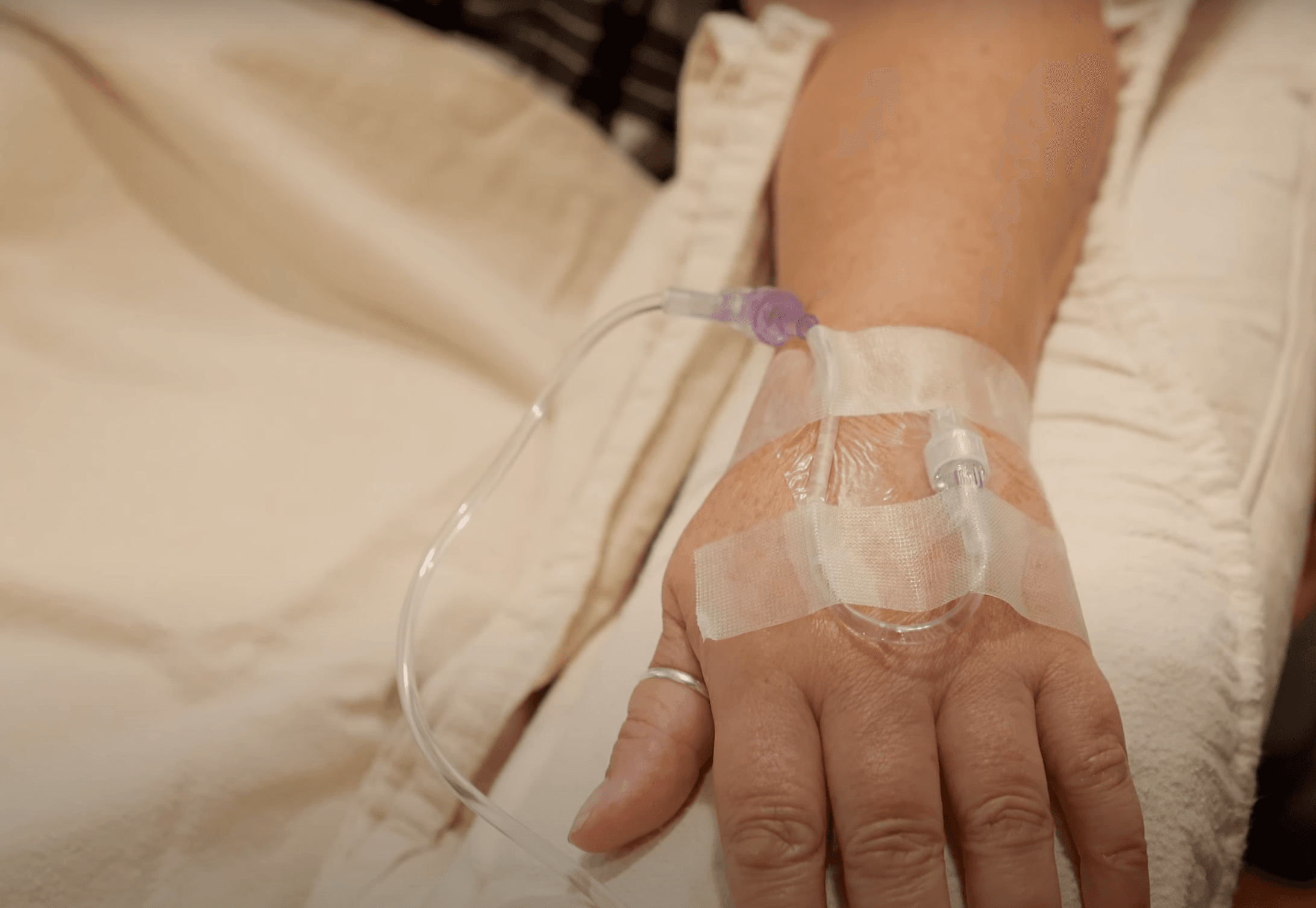 A plastic tube is connected to a hand with a ring on the patient's thumb.