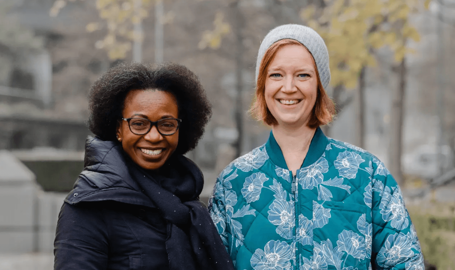 Two women standing side by side smiling.
