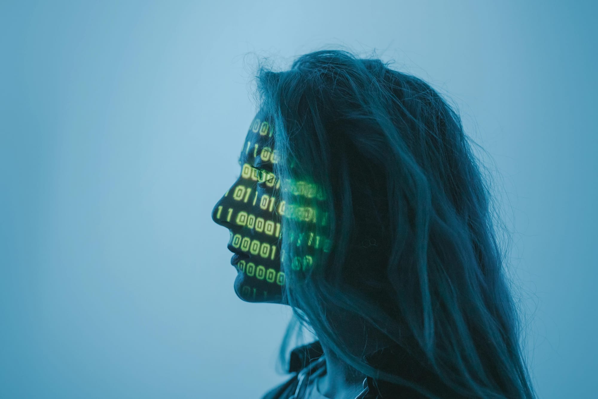 A woman in profile with binary code projected on her face.