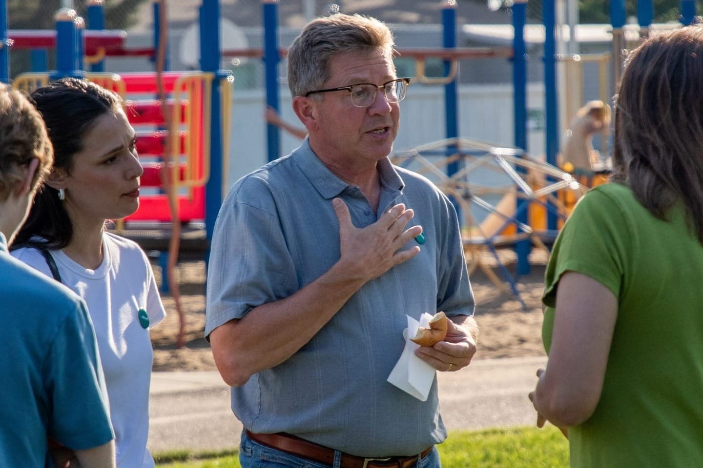 Tim Cartmell wears a light blue polo shirt as he talks to constituents on a playground in Edmonton.