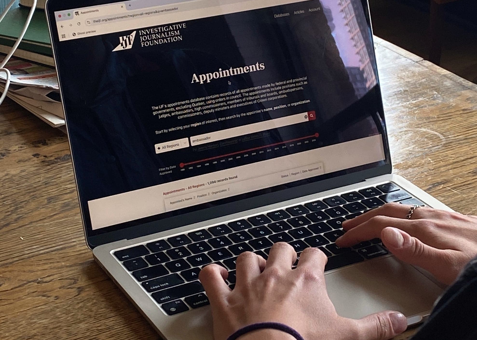 A pair of hands type on a laptop displaying the IJF's appointments database.