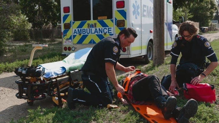 Two paramedics putting a person on a stretcher.