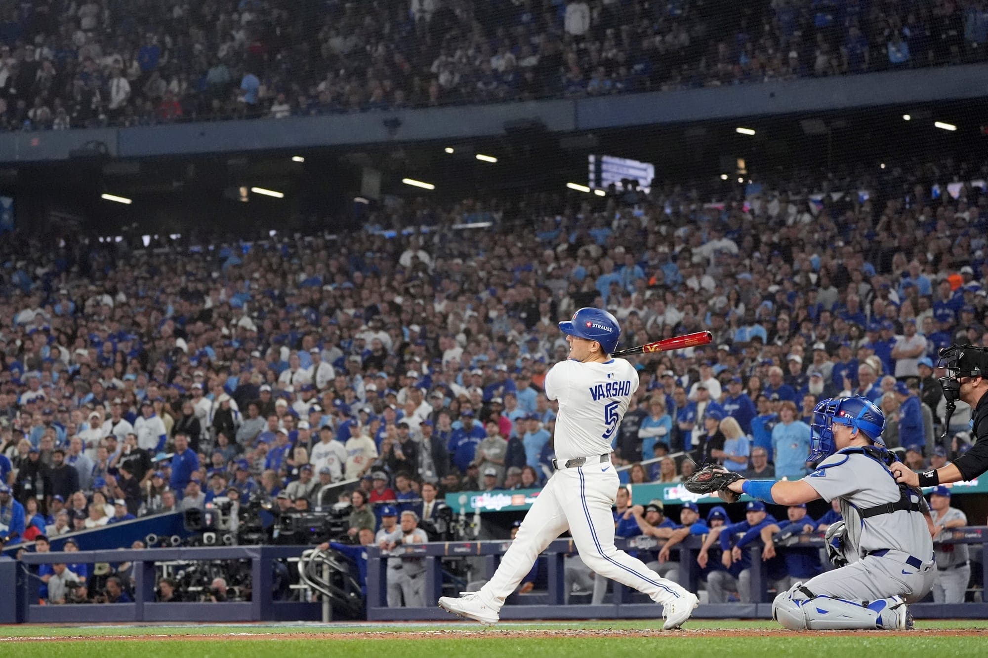 Daulton Varsho of the Toronto Blue Jays, in a white uniform, swings his bat.