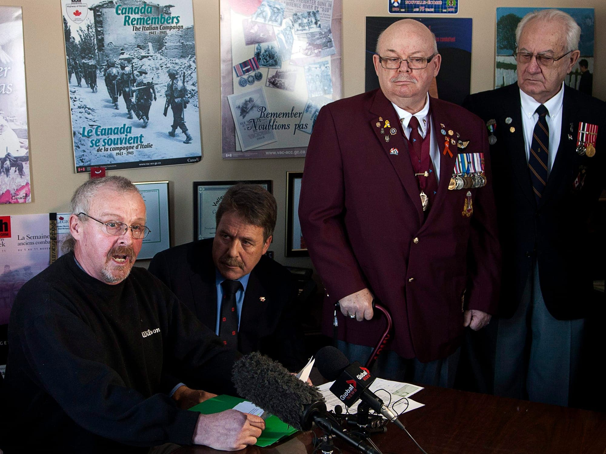 Keith Haynes speaks at a news conference as a local MP and retired service members look on.