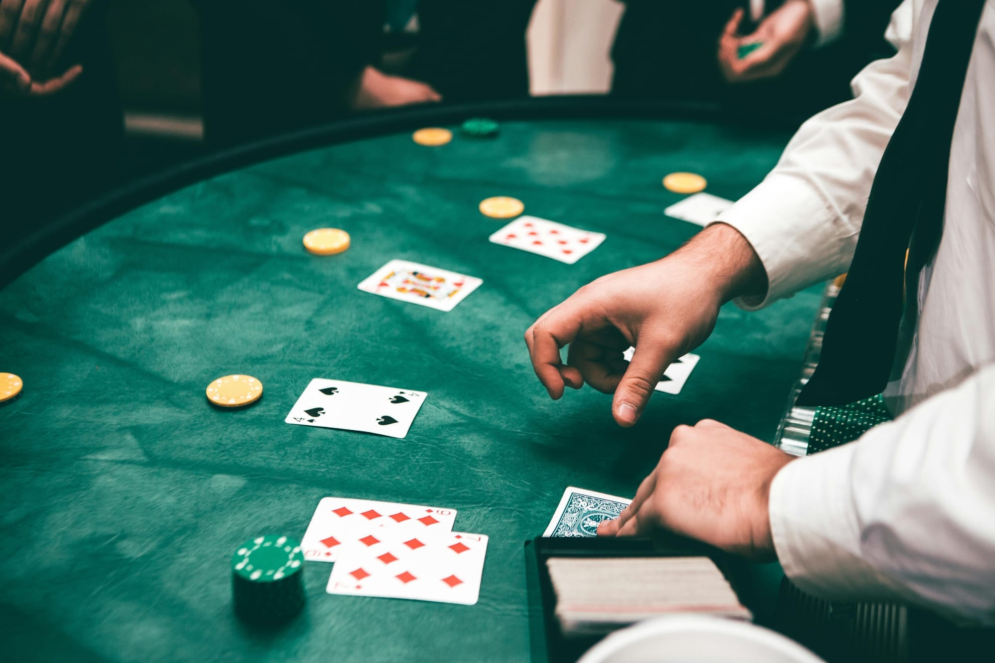 A a casino worker deals cards to players at a blackjack table.
