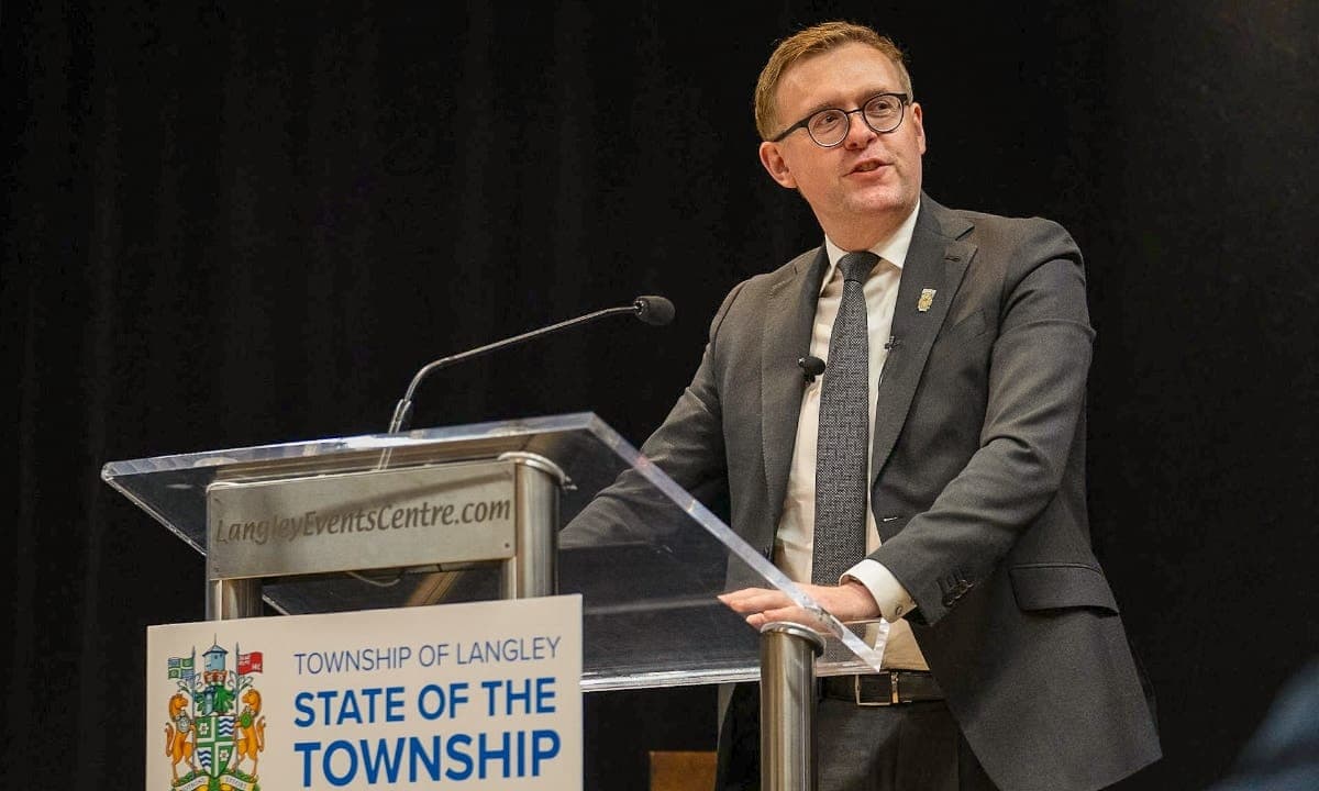 Eric Woodward wears a grey suit and tie as he speaks from a lectern reading 'Township of Langley: State of the Township.'
