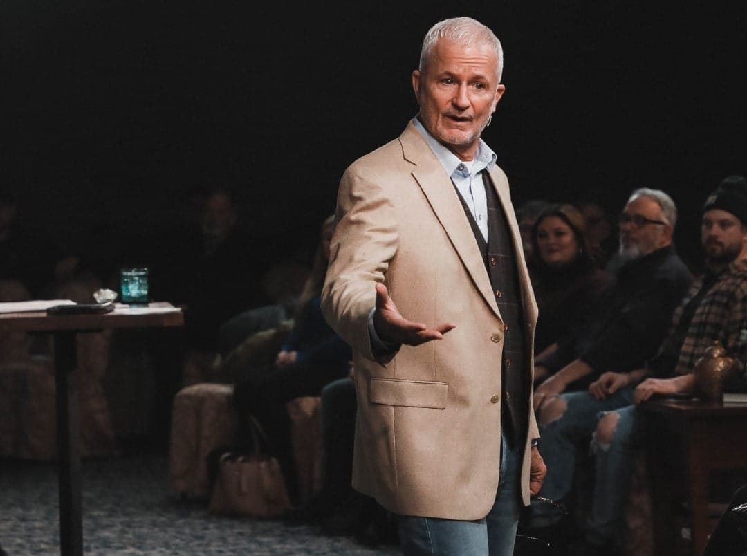 A man wearing a sport coat and vest speaks to a congregation.