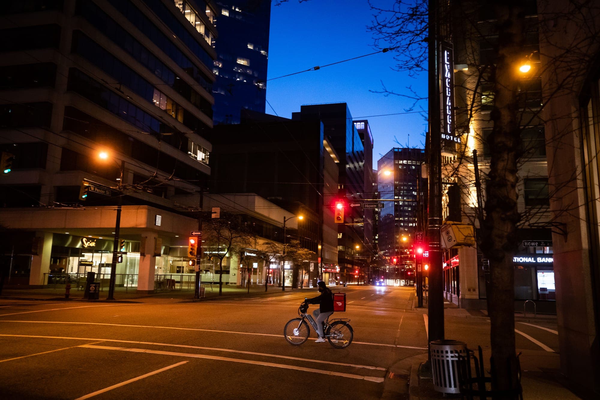 A DoorDash food delivery driver rides a bike in a very quiet downtown Vancouver, on April 5, 2020.