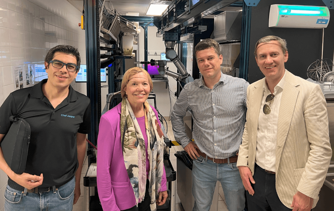 Four people wear hairnets while posing for a photo in a robotic kitch