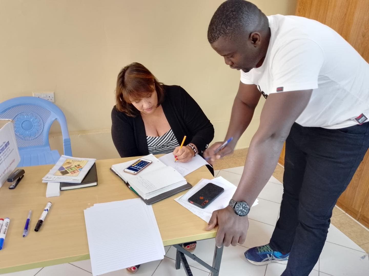 Tegemeza CEO Sarah Dunn takes notes as she speaks with the organization's administrator.
