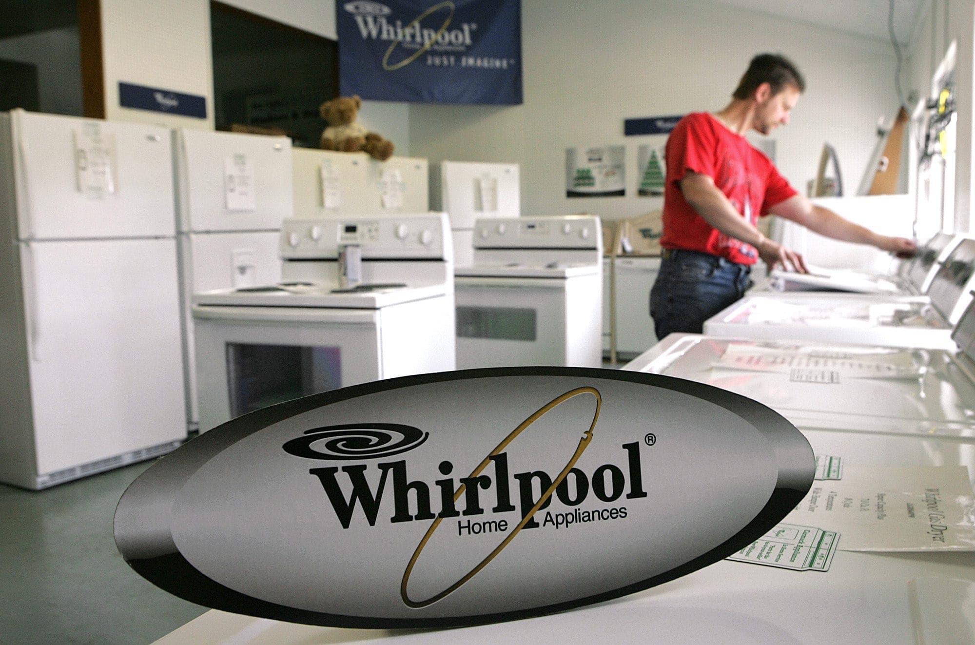 A man in a red t-shirt shops for a Whirlpool washing machine.