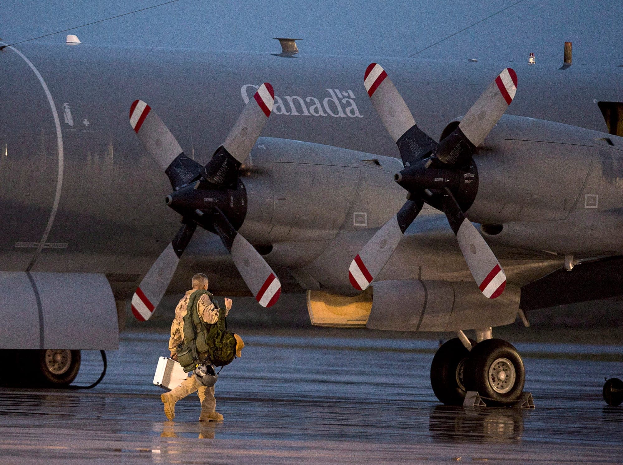 A member of the Canadian Armed Forces walks toward a reconnaissance aircraft.
