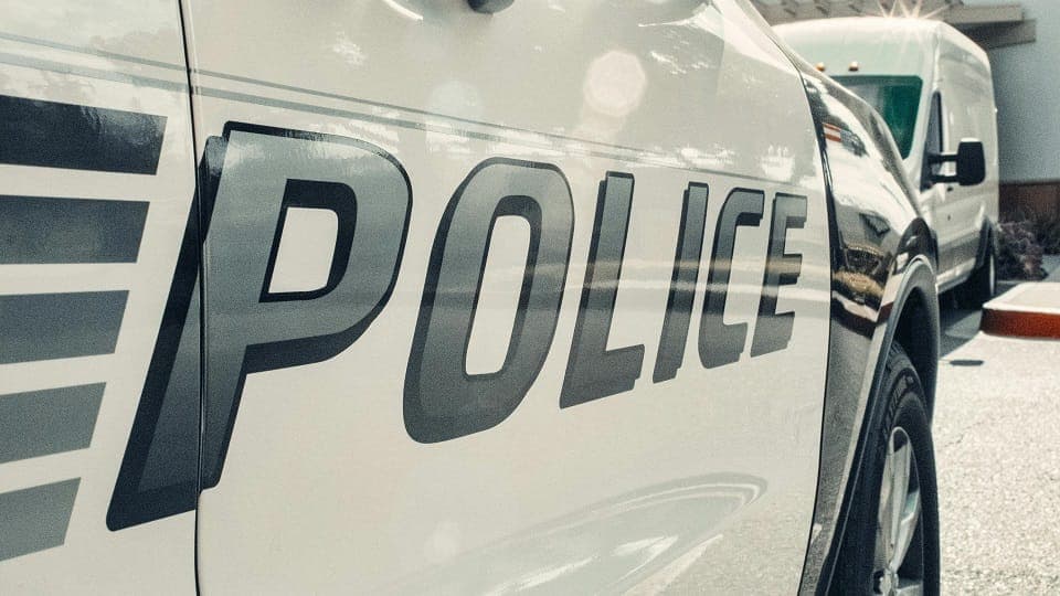 A close up of the word POLICE is seen on the door of a cruiser.