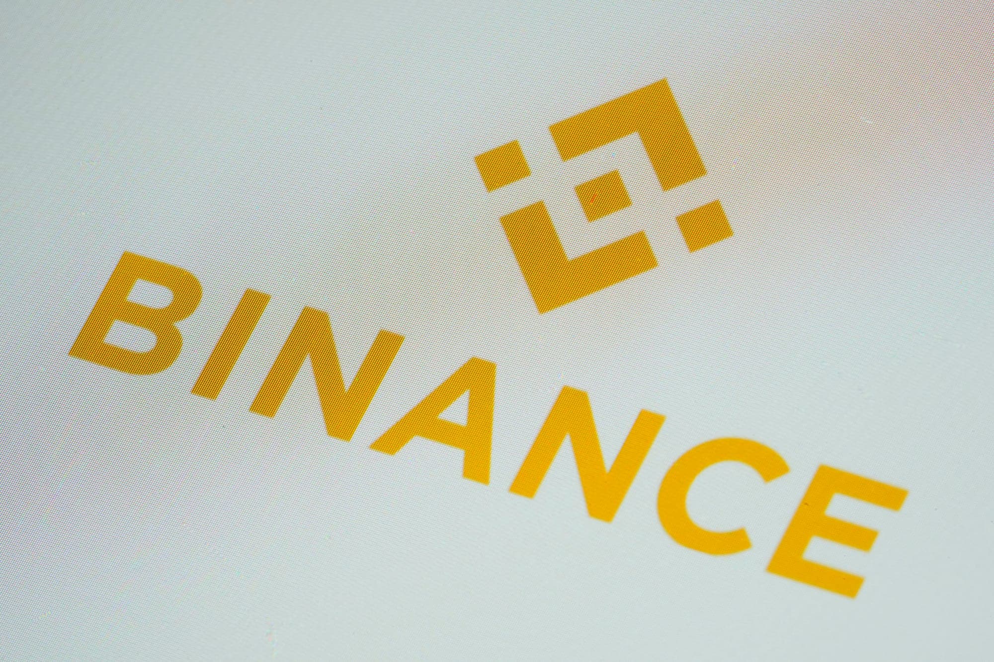 A yellow, diamond-shaped graphic above yellow text that says "Binance"