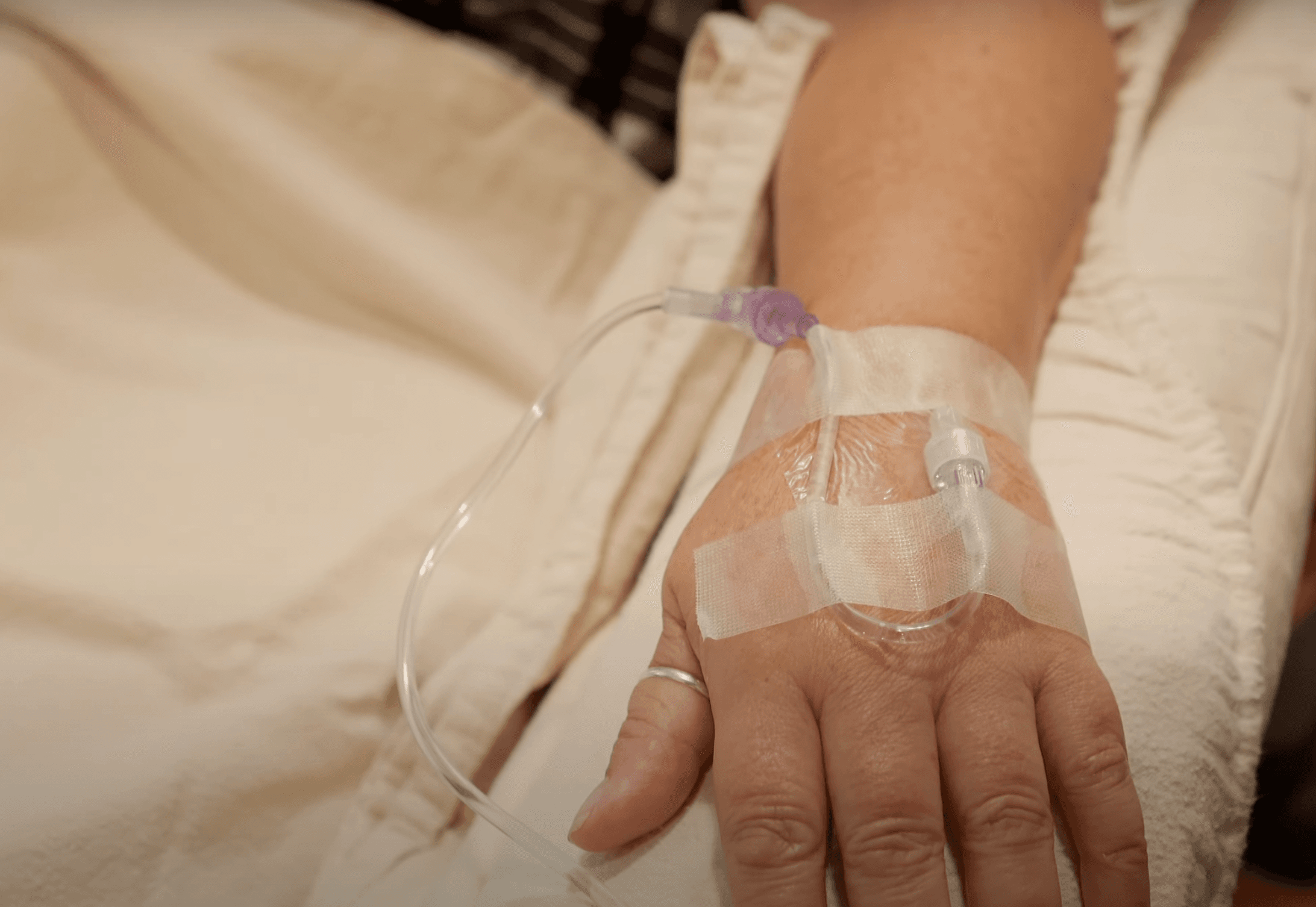A plastic tube is connected to a hand with a ring on the patient's thumb.