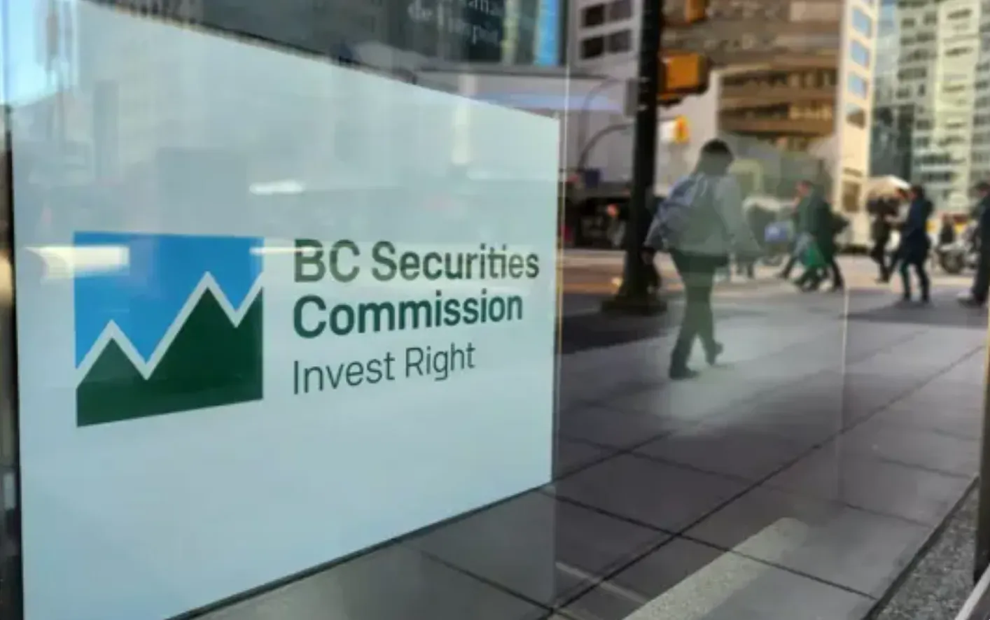 A white sign with the blue and green logo of the B.C. Securities Commission is pictured in a window in downtown Vancouver.