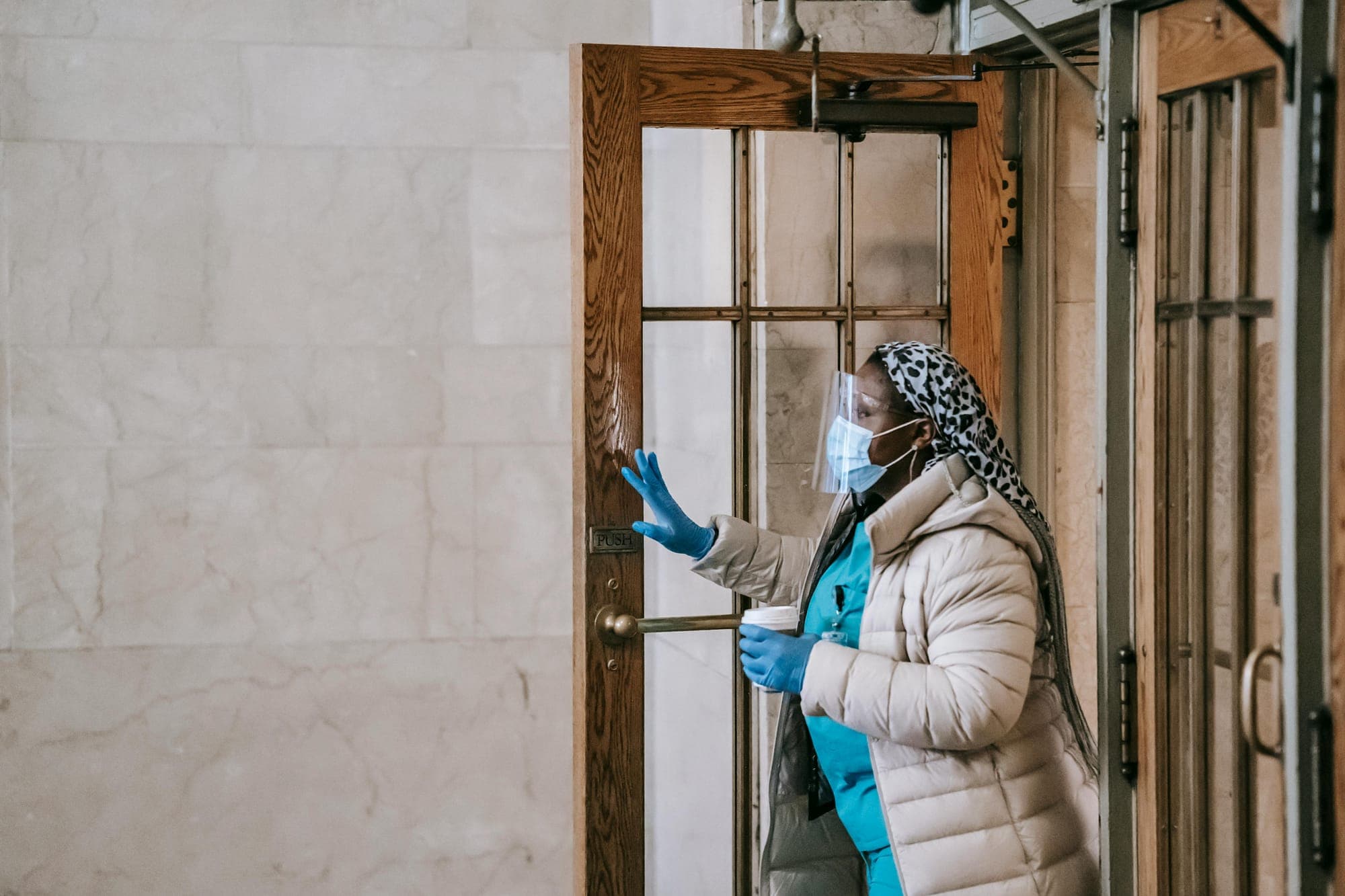 A nurse in a respirator and gloves leaves a building.