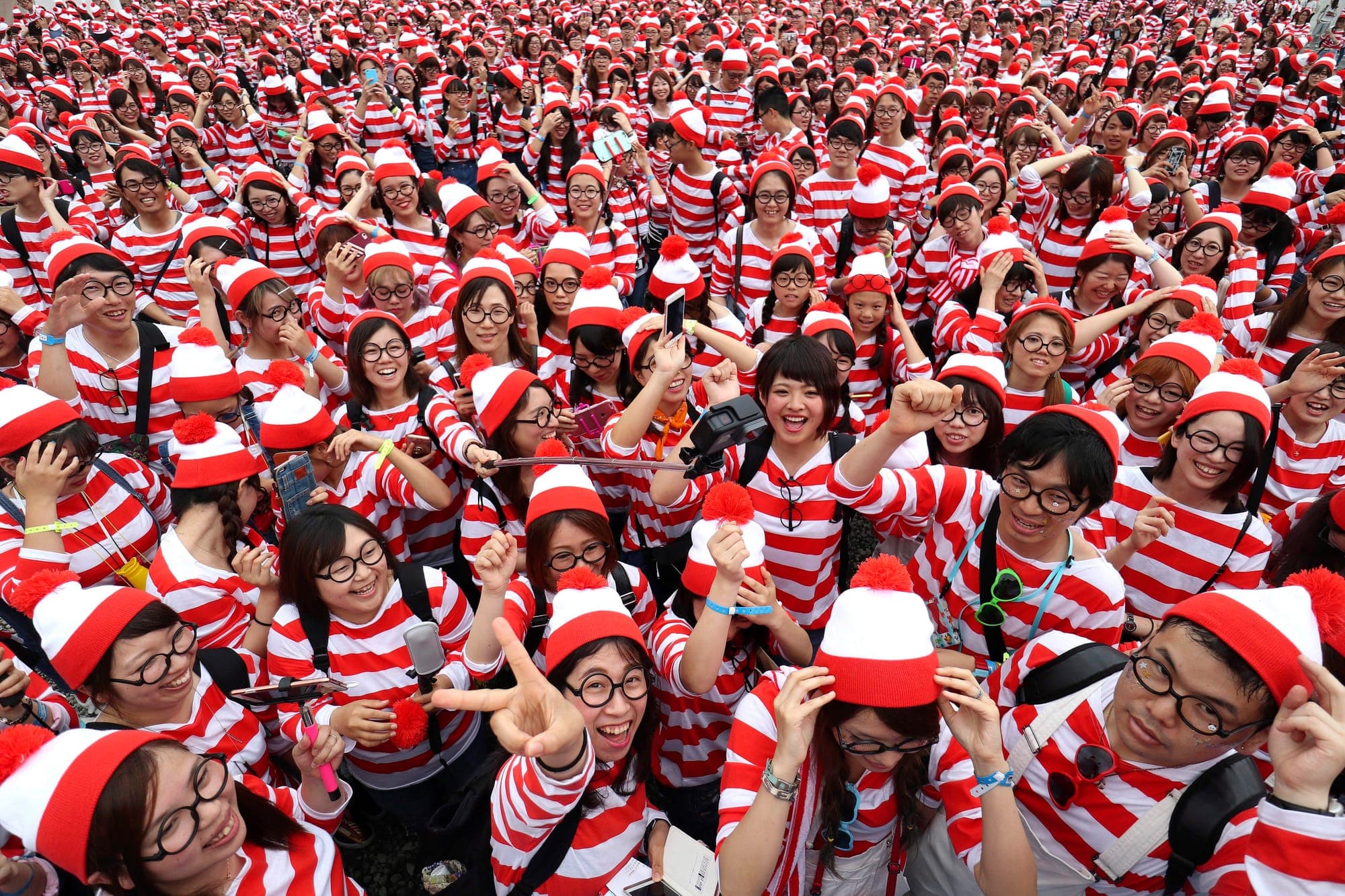A large crowd of participants dressed as Waldo of Where's Waldo pose together at an event in Japan.