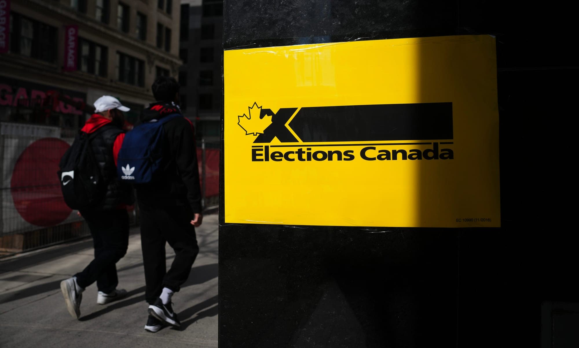 People walk past an Elections Canada sign outside an office in Montreal on April 15, 2025.