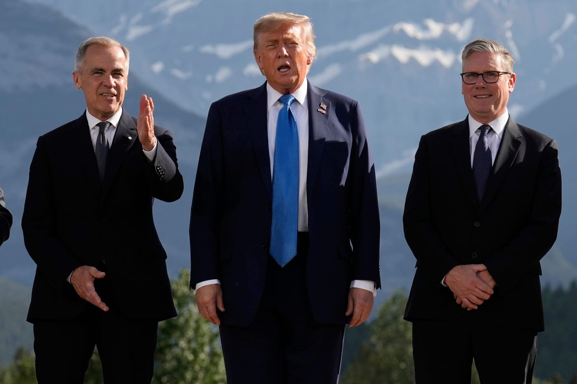 Mark Carney, Donald Trump and Keir Starmer stand in front of a mountain background.