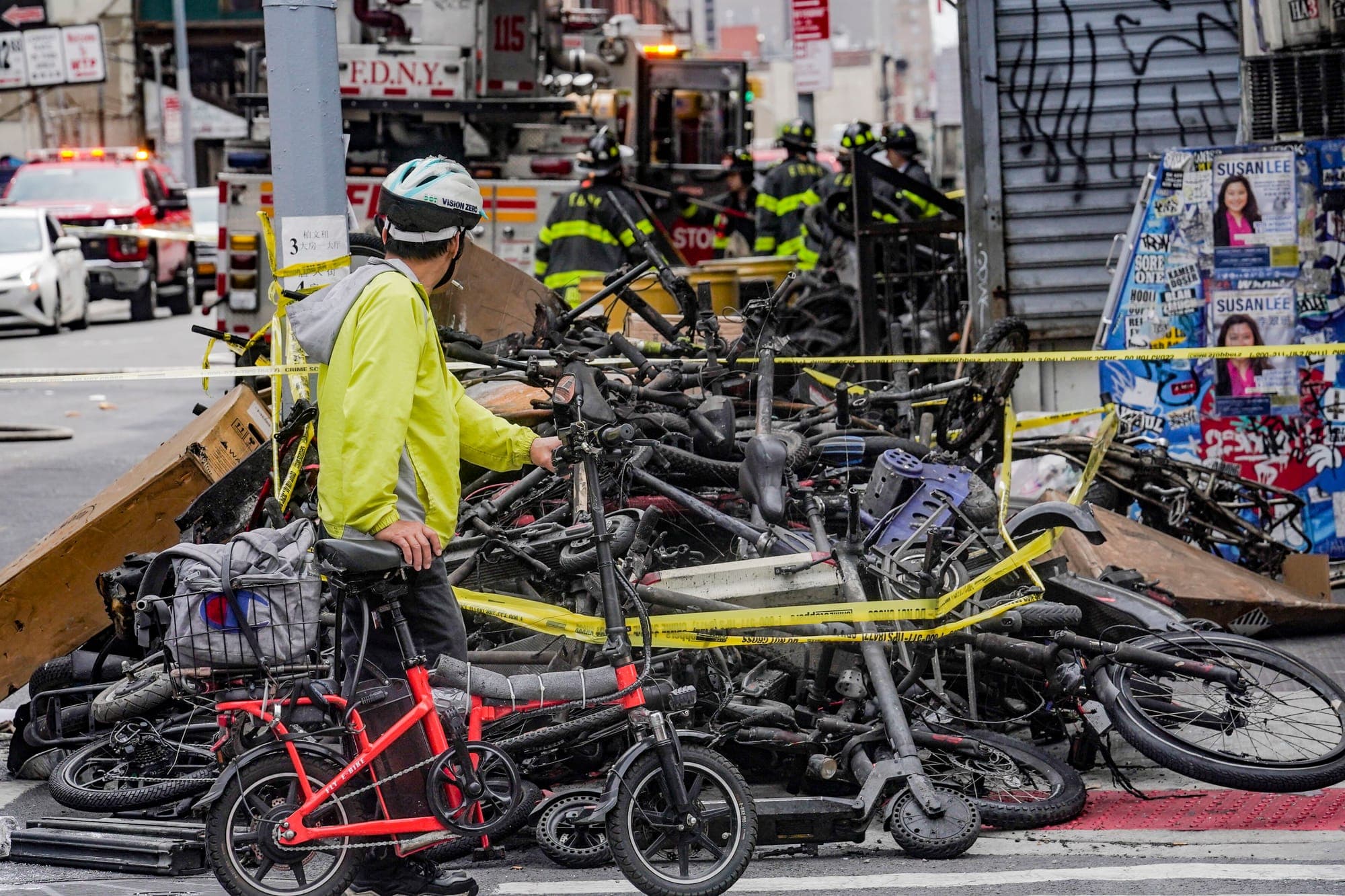 A biker stops to look at a pile of e-bikes in the aftermath of a fire in Chinatown on June 20, 2023, in New York.