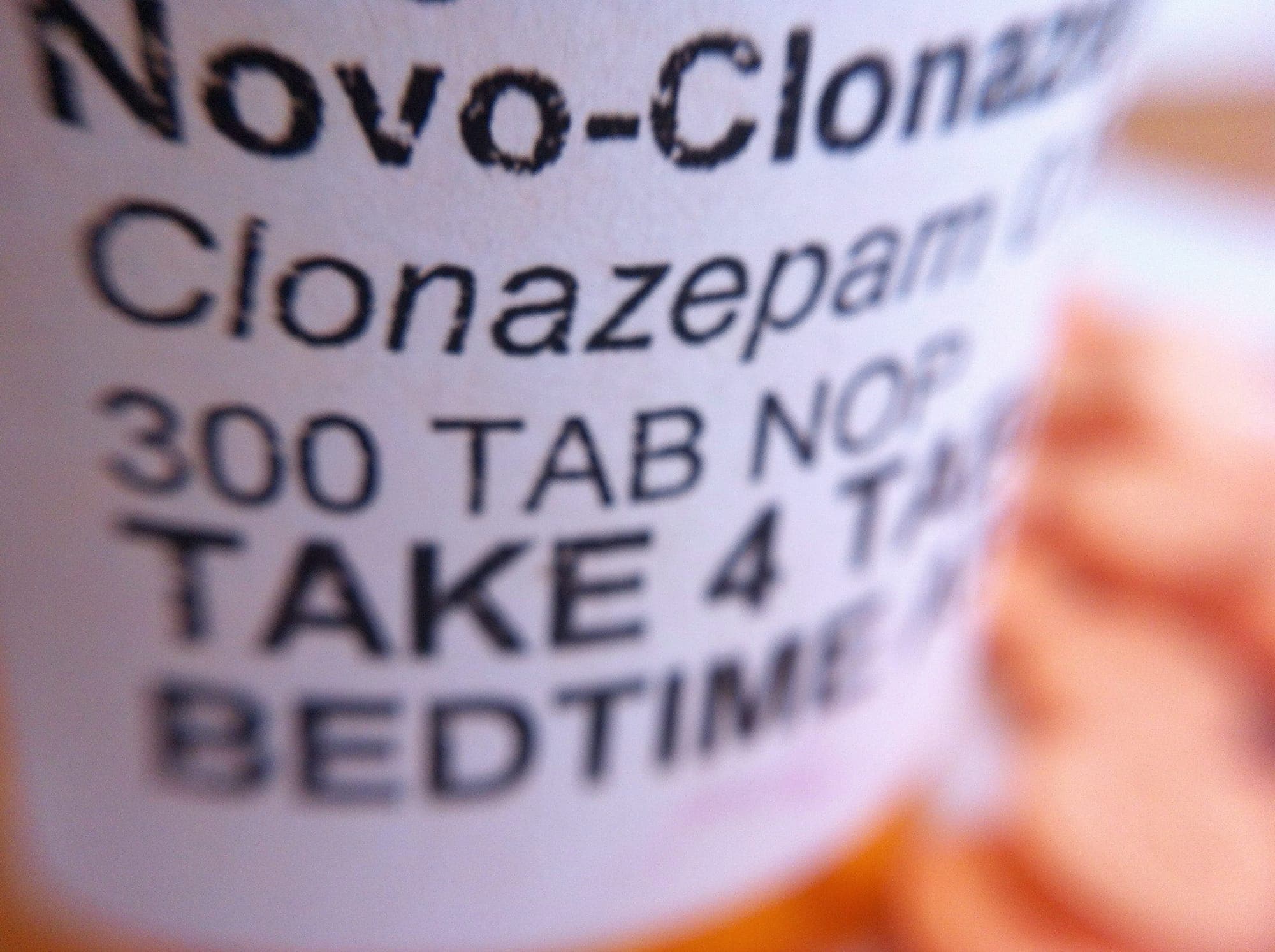 A prescription pill bottle containing clonazepam is shown in close-up.