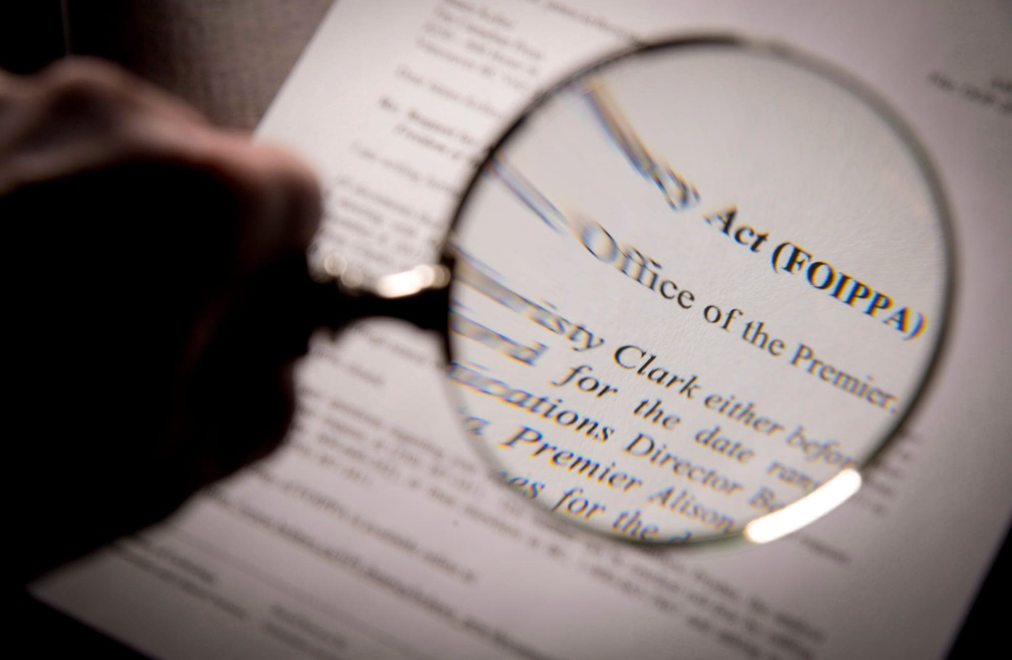 A hand holds a large magnifying glass over text.