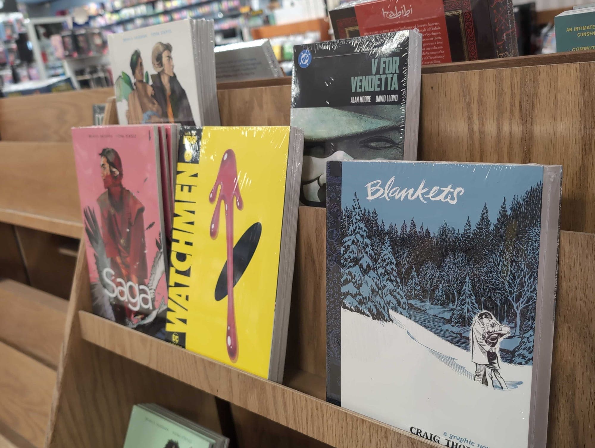 Graphic novels Blankets, Watchmen, V for Vendetta and others are shown on a shelf.