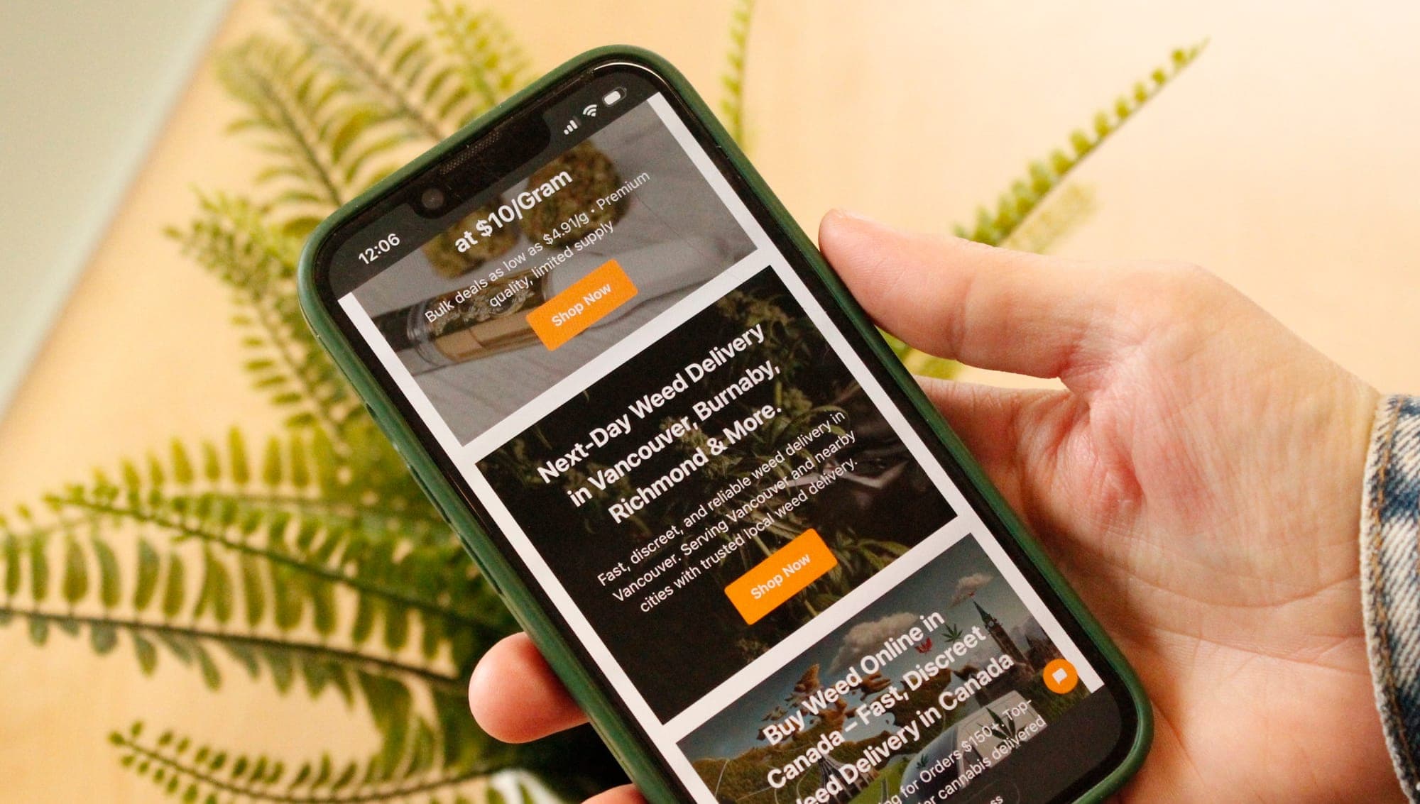 A hand holds a phone showing a website advertising cannabis sales.