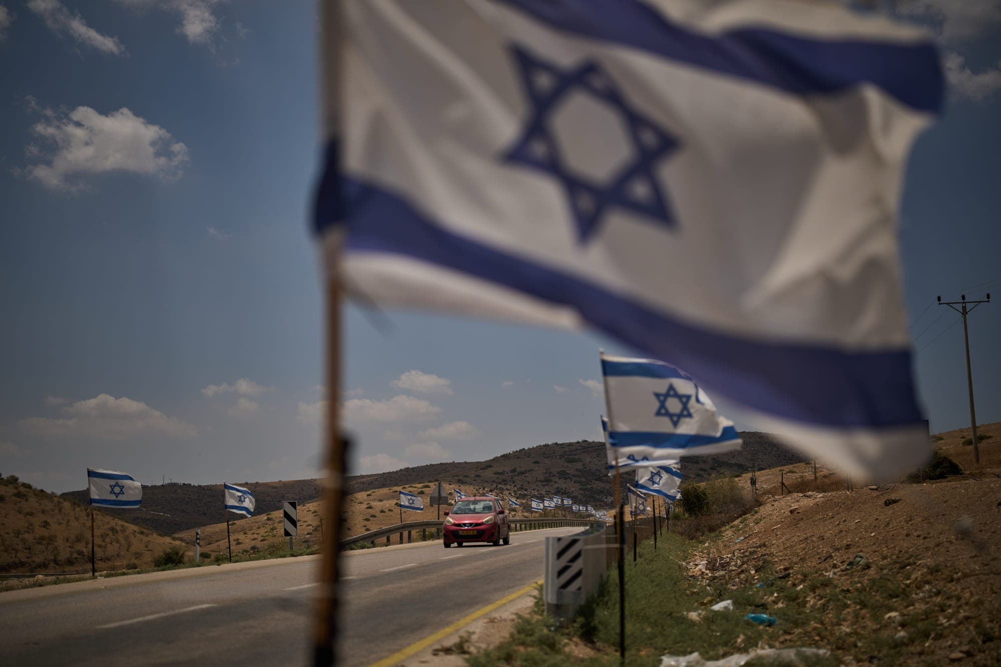 A car drives past Israeli flags lining a road in the northern Jordan Valley of the occupied West Bank, on June 24.
