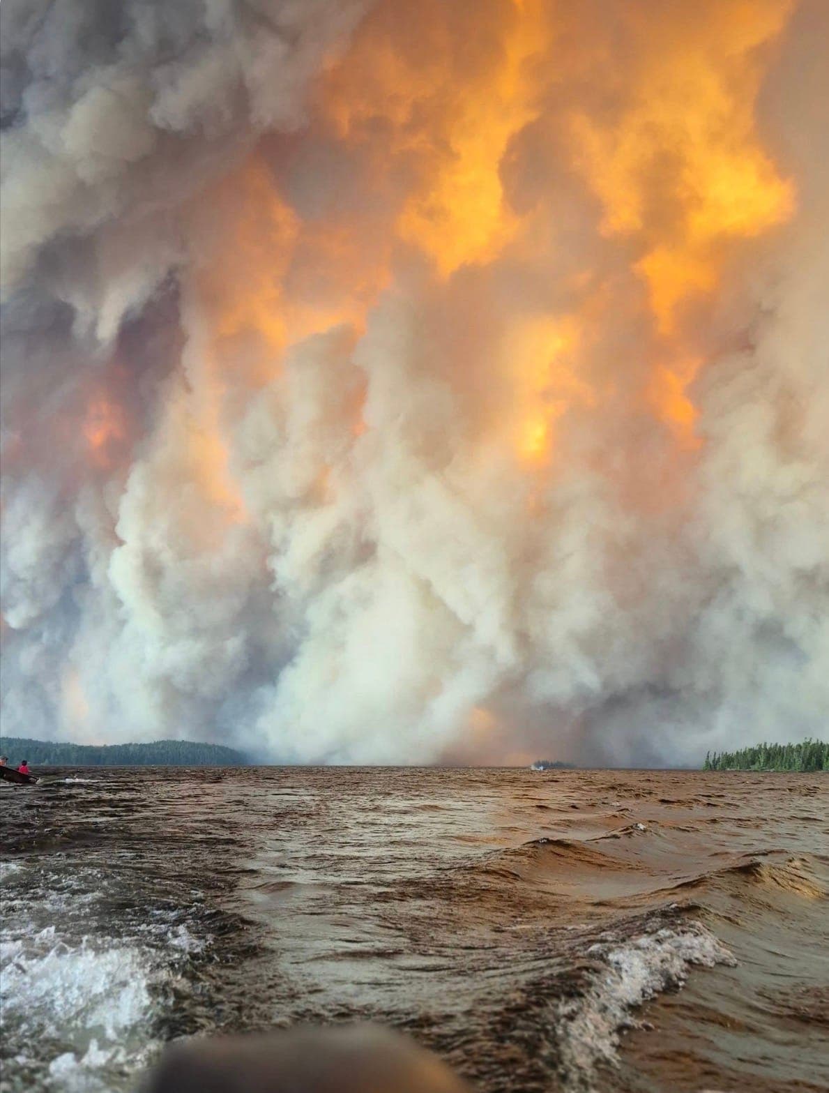 Smoke fills the sky with fire as evacuees escape on boat from their First Nation.