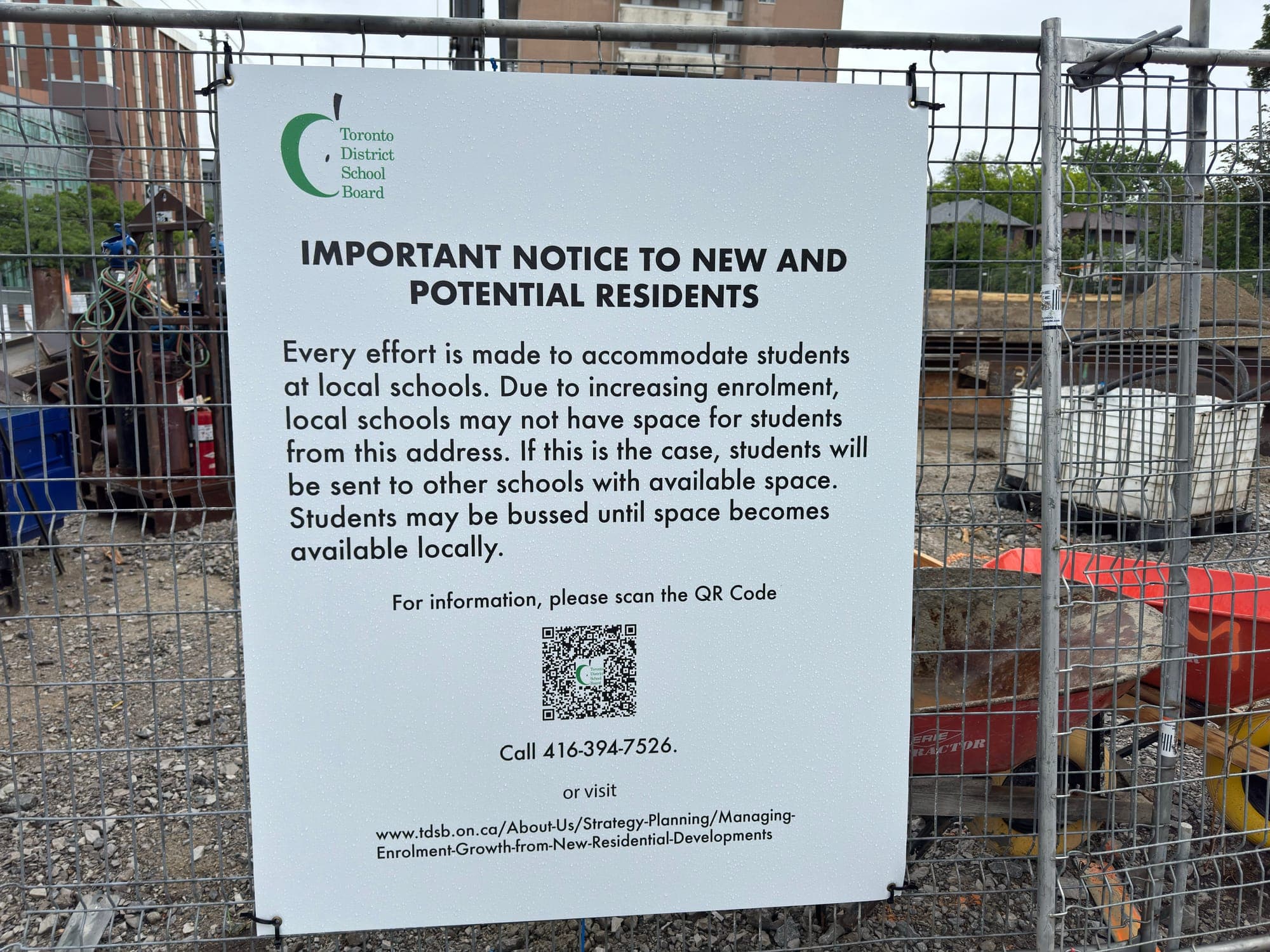 TDSB sign on a construction fence reading: local schools may lack space due to rising enrolment; students may be bused elsewhere until space opens. Contact info and QR code included.