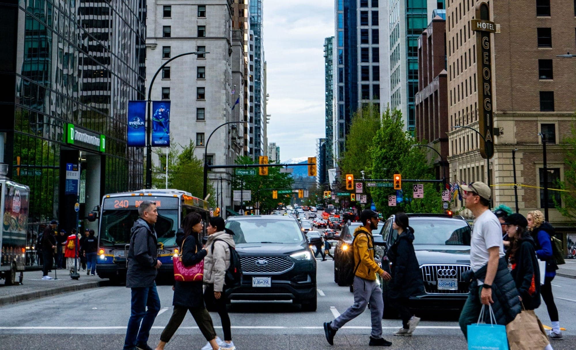 Pedestrians cross a busy street in downtown Vancouver.
