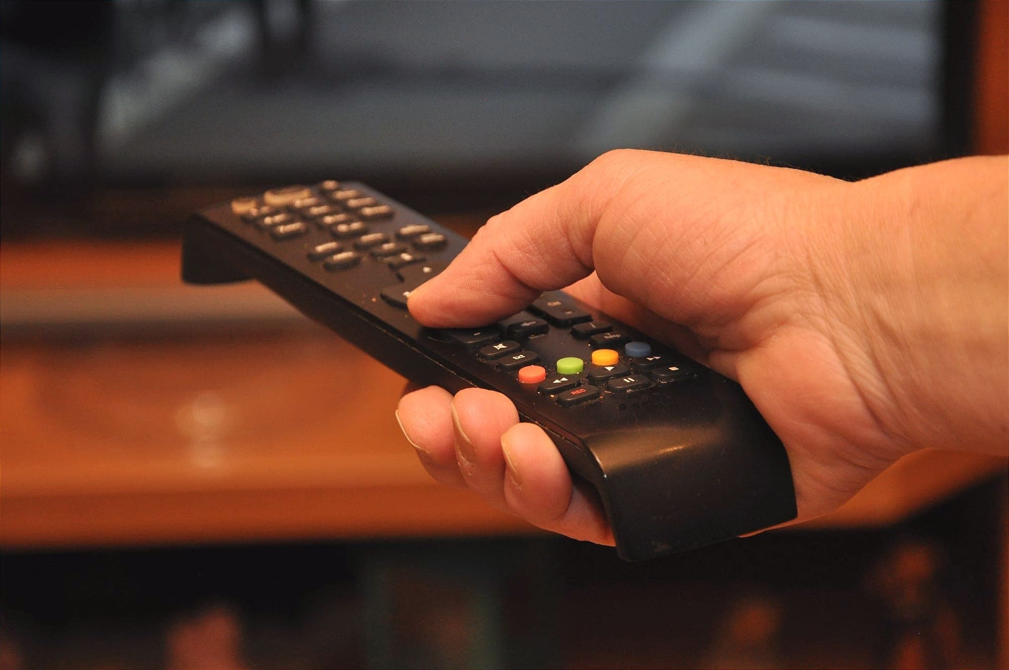 A person pushes a button on a TV remot