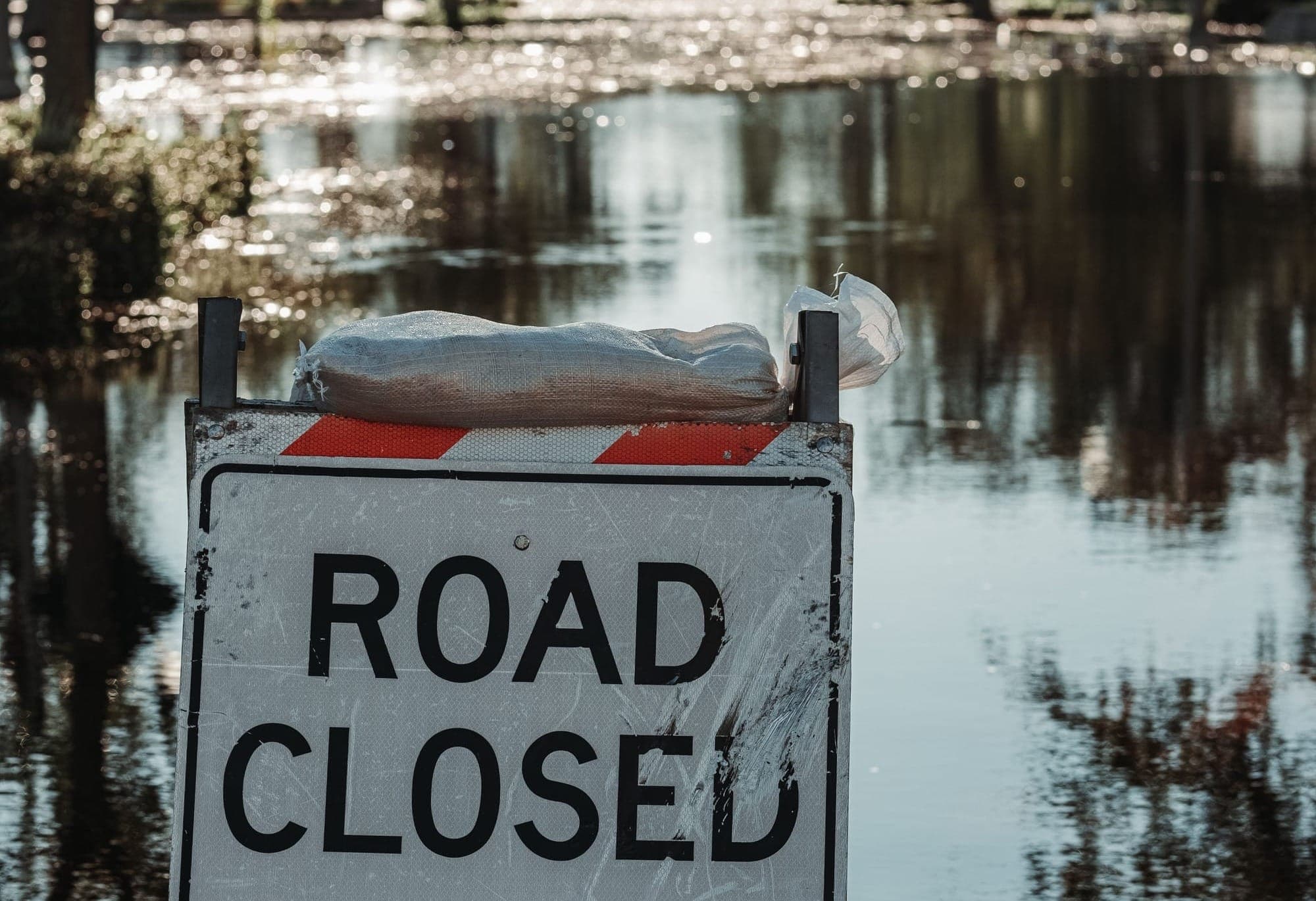 A "ROAD CLOSED" sign is shown in front of a flooded area