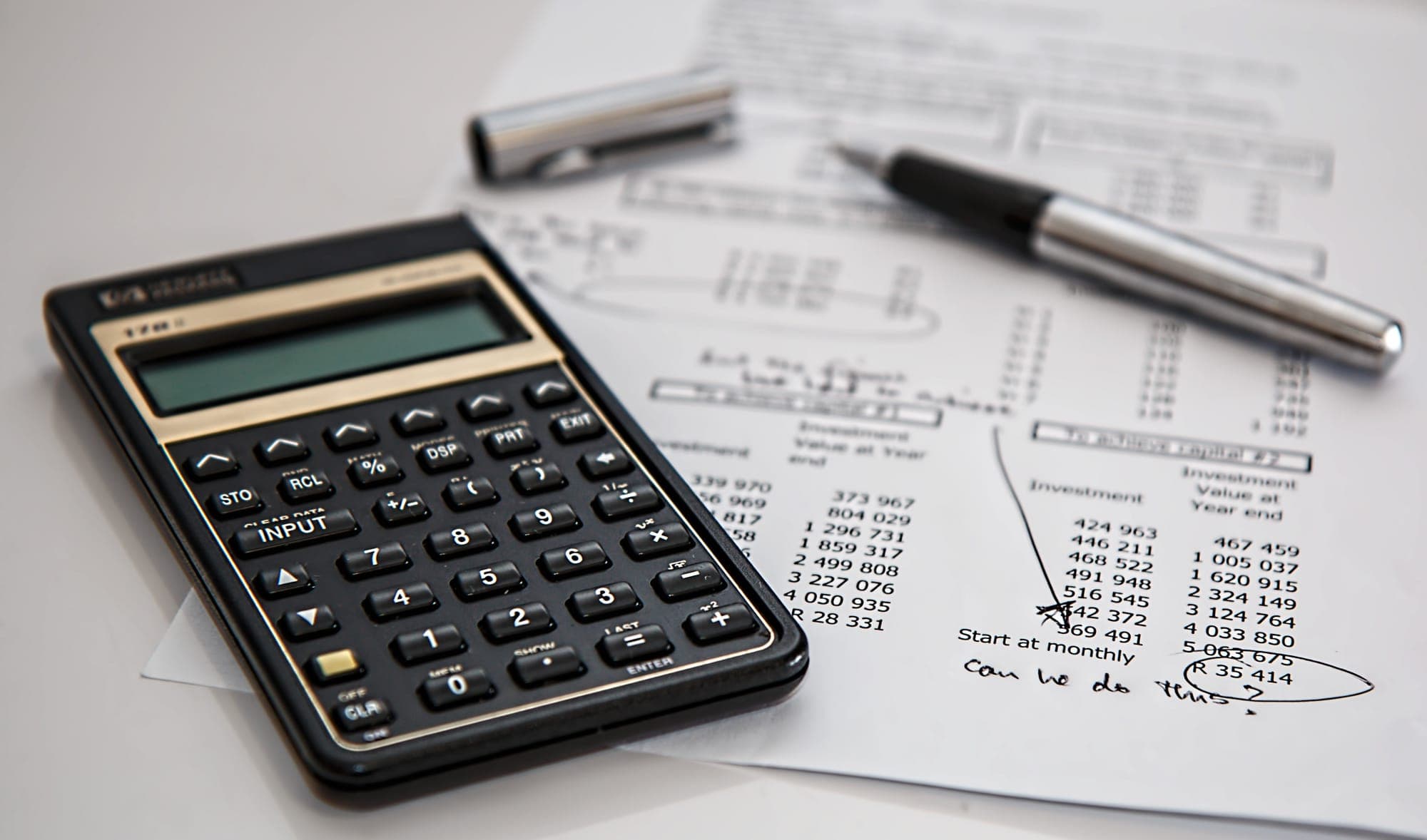 A calculator lays on top of marked- financial documents.