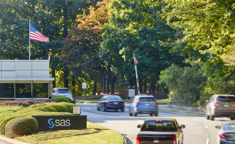 Cars are seen driving to the SAS headquarters, next to a sign with the SAS logo and an American flag.