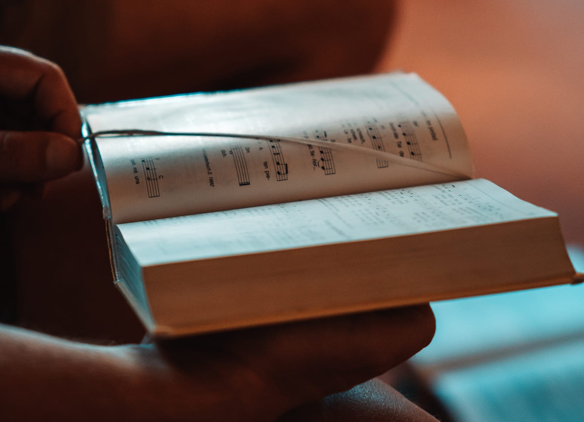 A photo of a person's hands holding a hymn book.