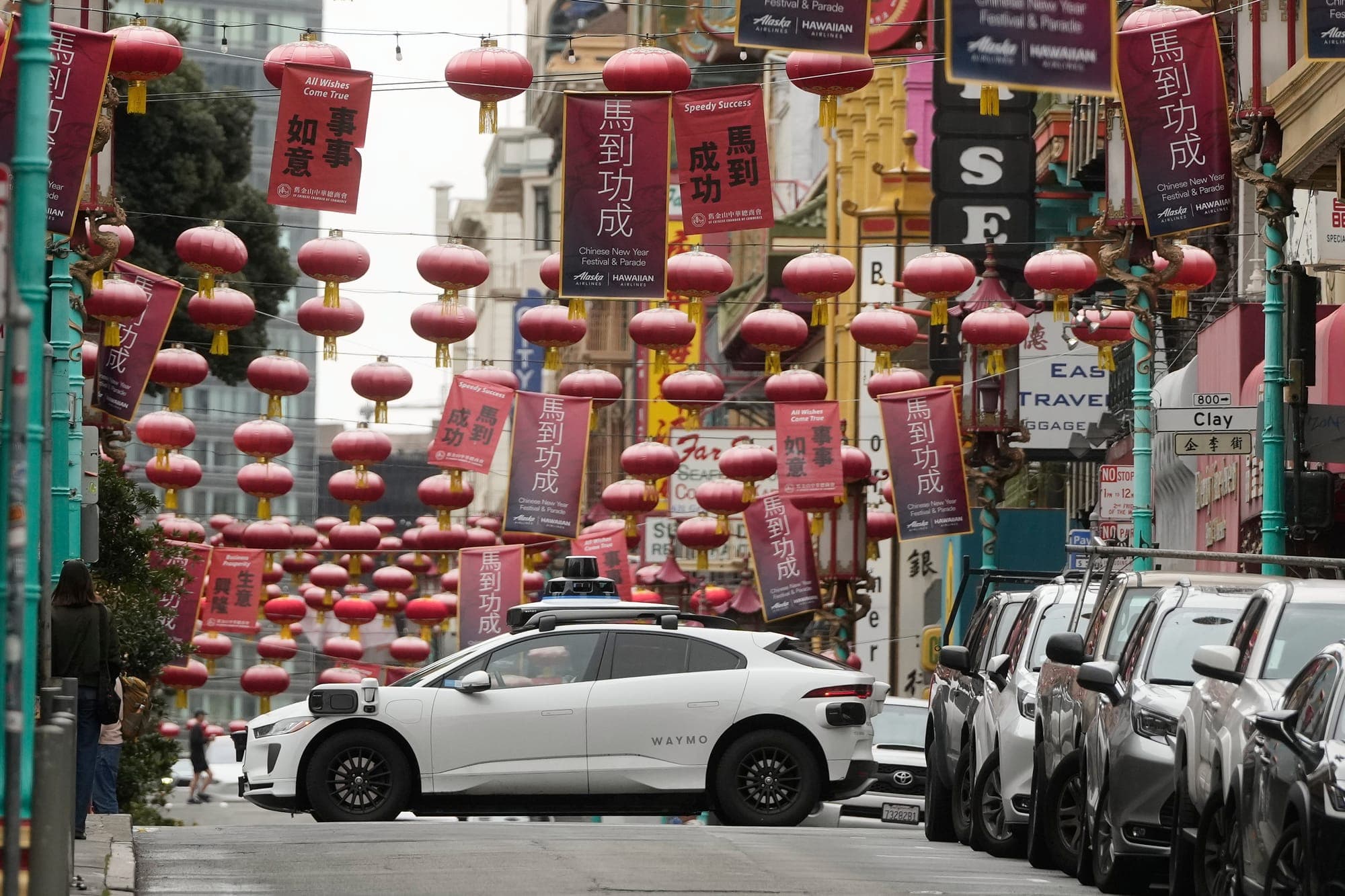 A Waymo autonomous vehicle drives below lanterns hanging in Chinatown in San Francisco on Feb. 25.